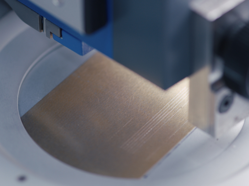 A piece of aluminium sheet being inspected under a lab device.
