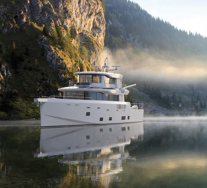Arksen 85 Explorer Yacht auf dem Wasser vor Bergen und Bäumen.