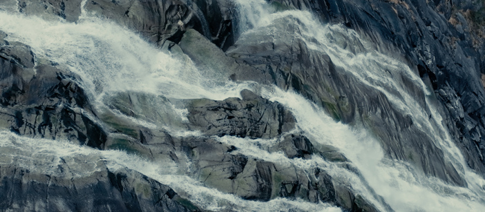 En foss som går langs en steinete fjellvegg.