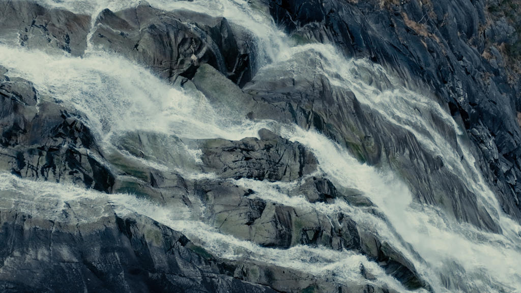 Ein Wasserfall, der entlang einer steinigen Bergwand fließt.