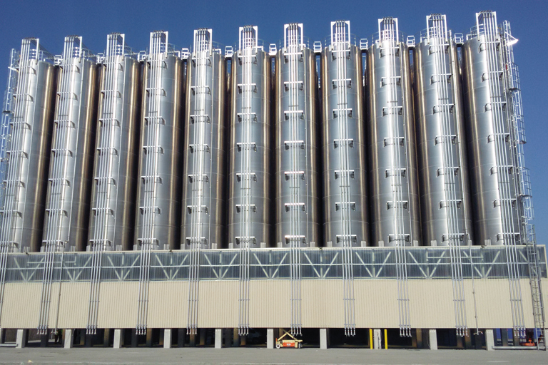Industrial silos with aluminium components in front of a blue sky.