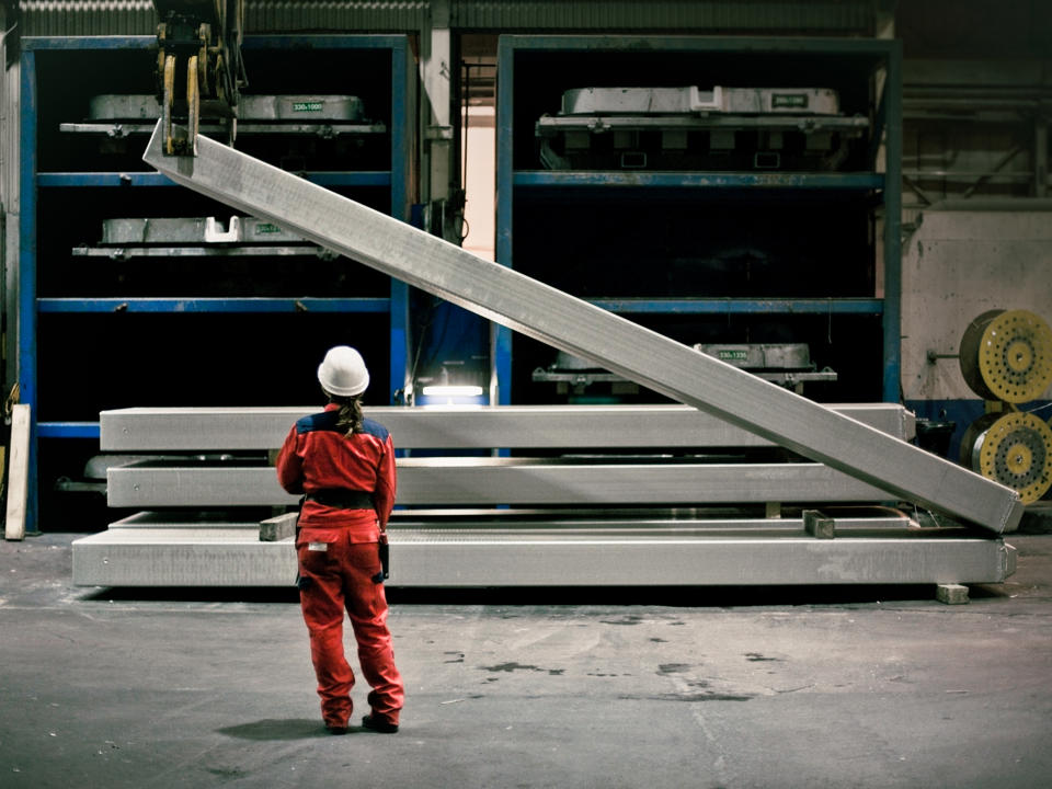 Speira-Mitarbeiter in einer Fabrik, der vor Aluminiumgütern steht, die angehoben werden.