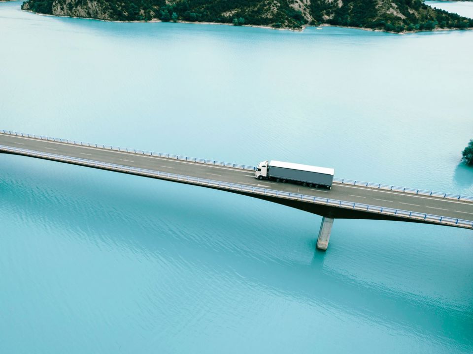 A truck drives over a bridge that crosses a body of water.