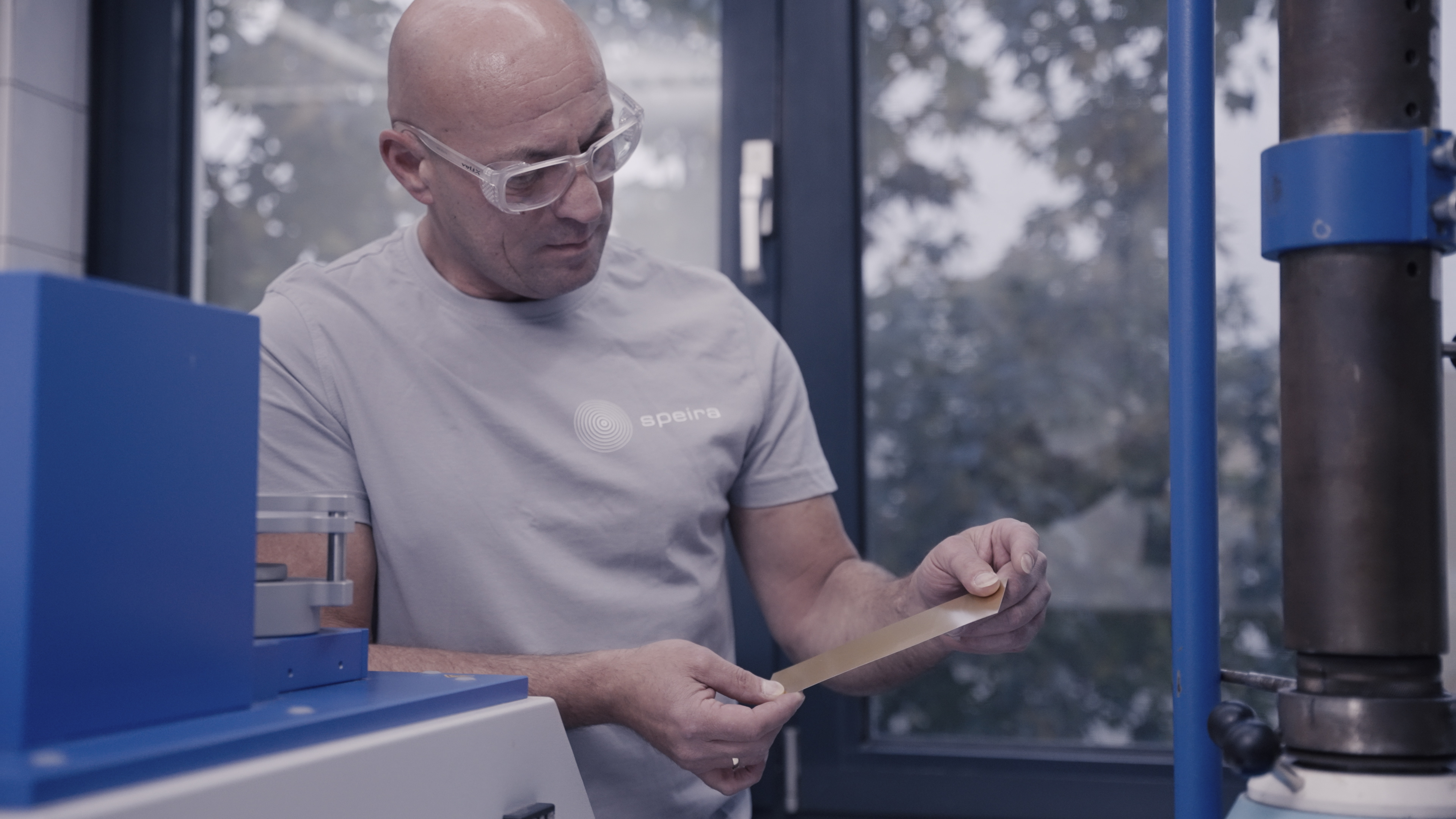 A Speira lab technician inspects material in protective equipment.