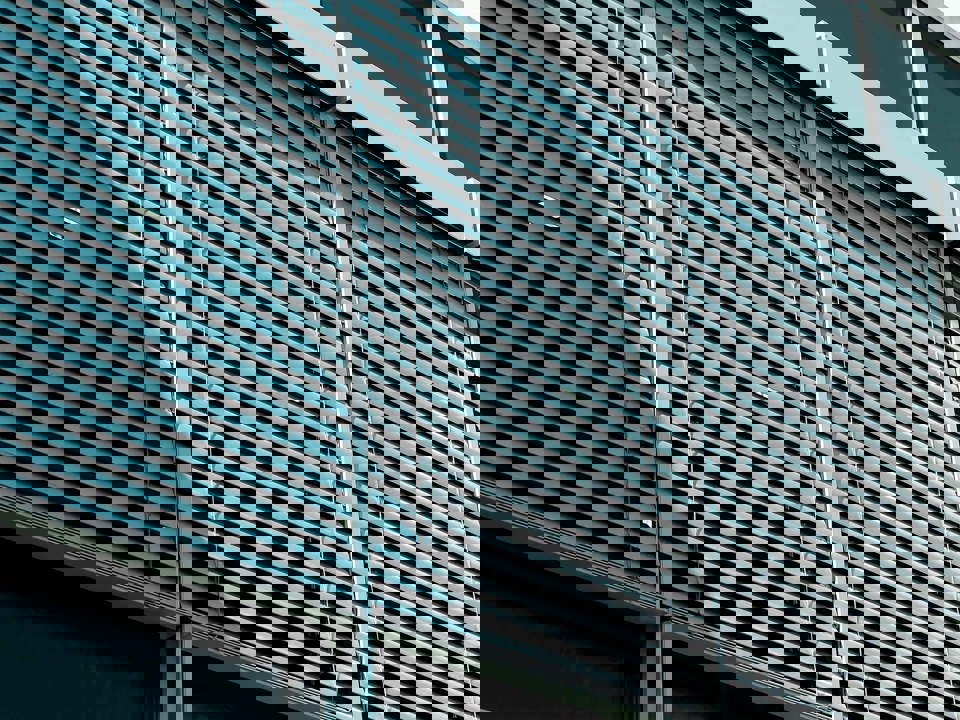 Aluminium raffstores in front of a modern building’s window front.