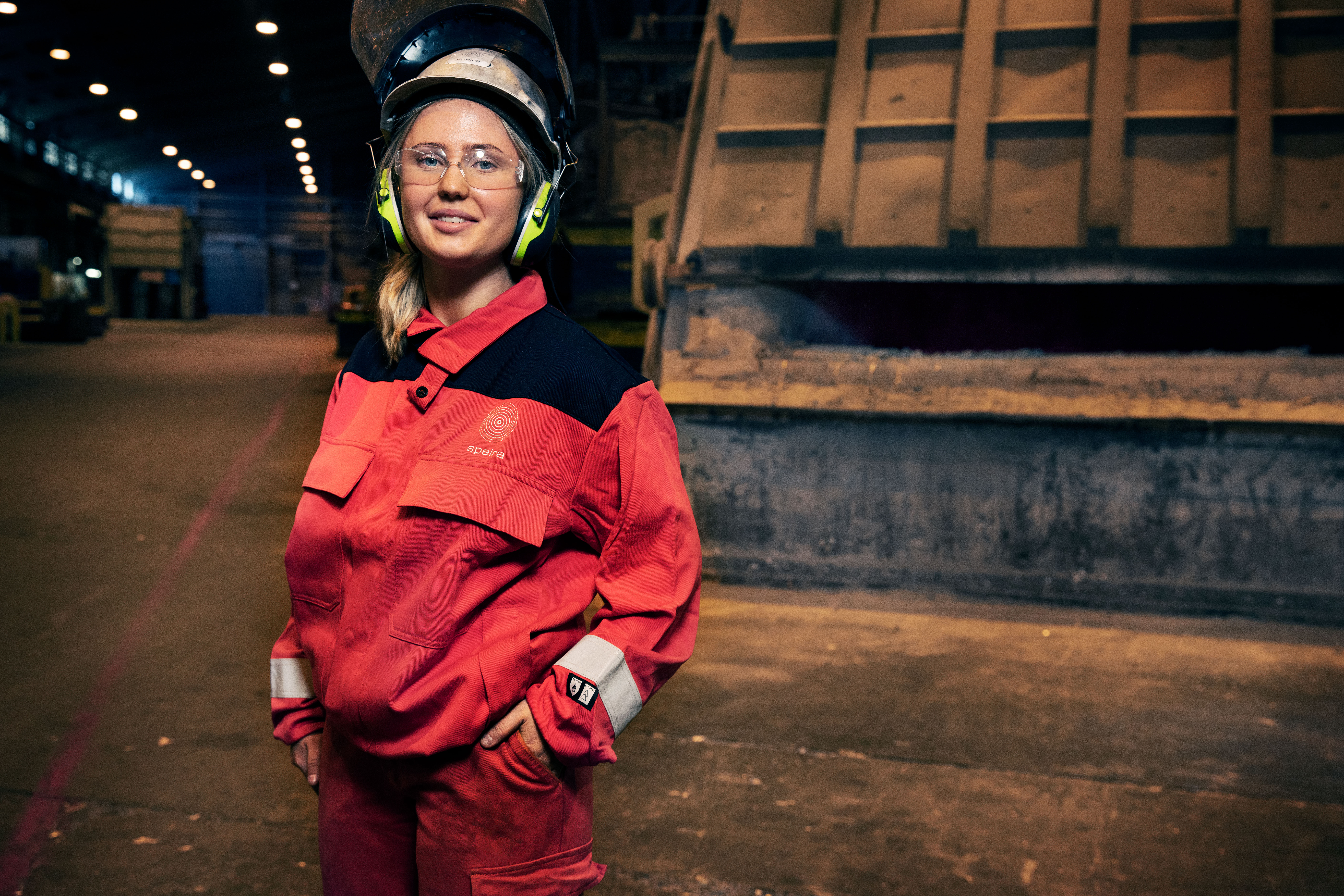 A young smiling employee in work clothes at a Speira plant.