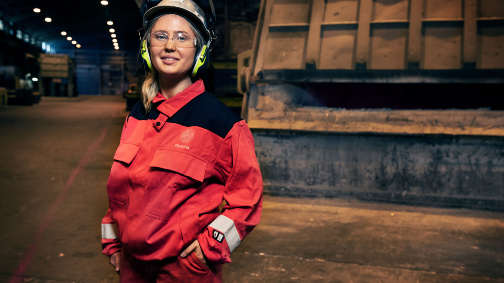 Eine junge lächelnde Mitarbeiterin in Arbeitskleidung in einem Speira Werk.