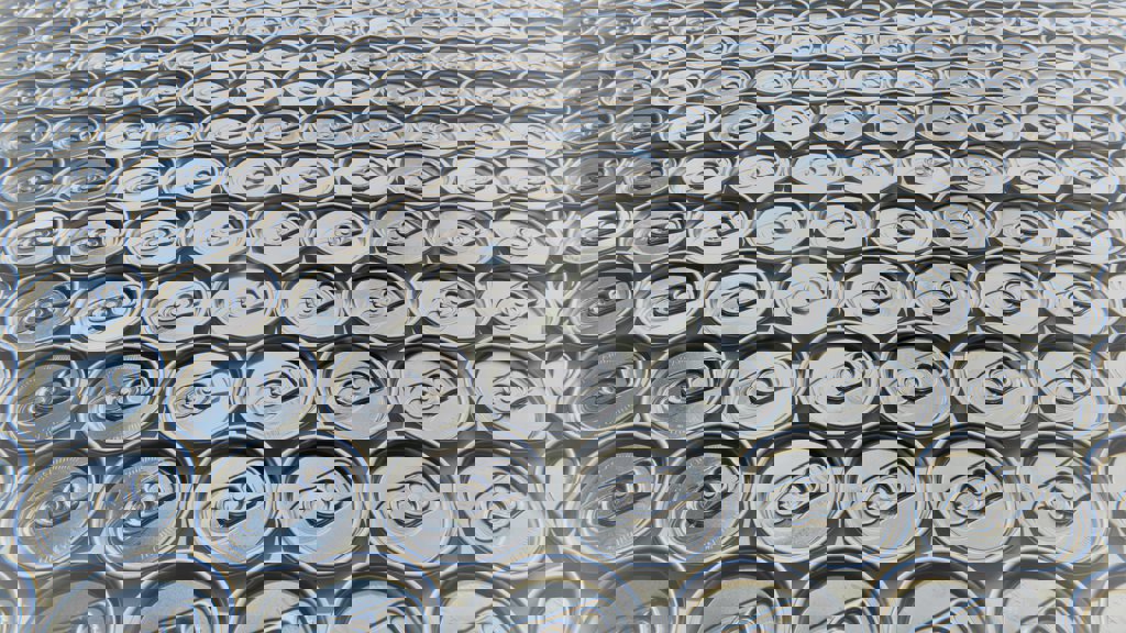 The top of aluminium cans, geometrically aligned next to each other.