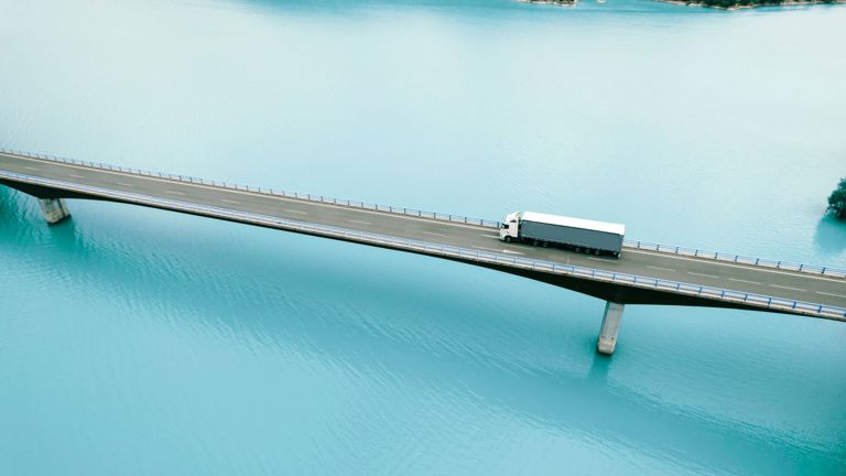 En lastebil kjører over en bro som går over et vann.
