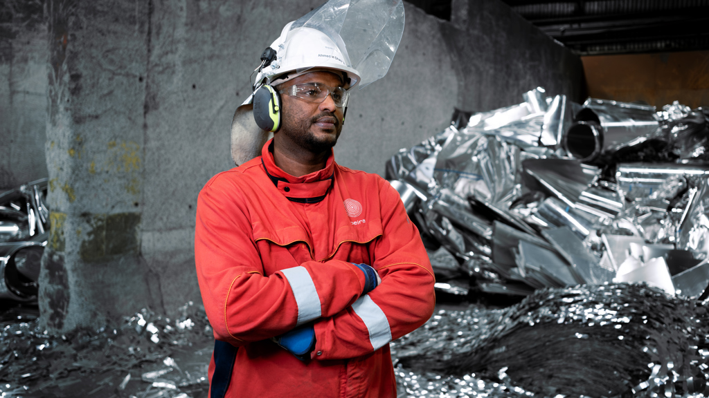 Speira-Mitarbeiter in seiner Arbeitskleidung vor Aluminiumschrott.