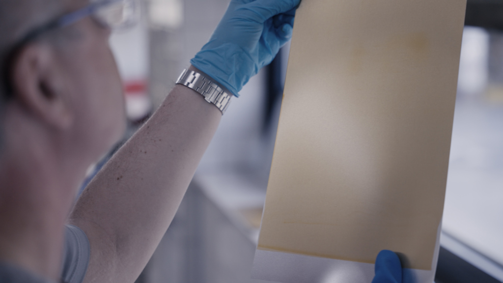 A lab worker in Speira holding a piece of aluminium sheet for inspection.