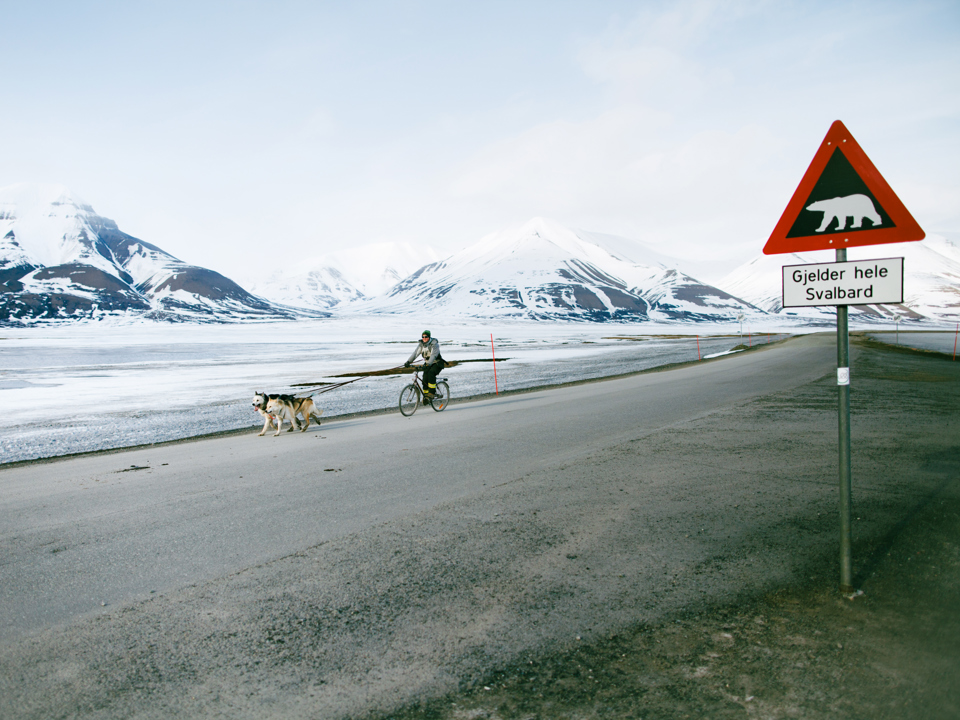 Street signs made of aluminium standing in front of a snowy landscape with mountains.