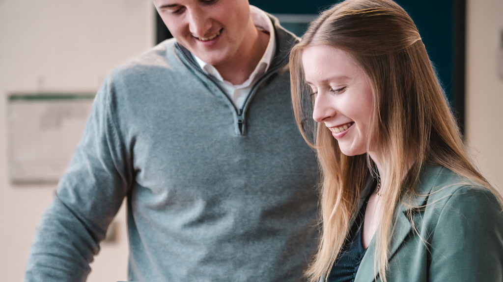 To unge Speira-kolleger sitter og ser på et nettbrett sammen på kontoret.