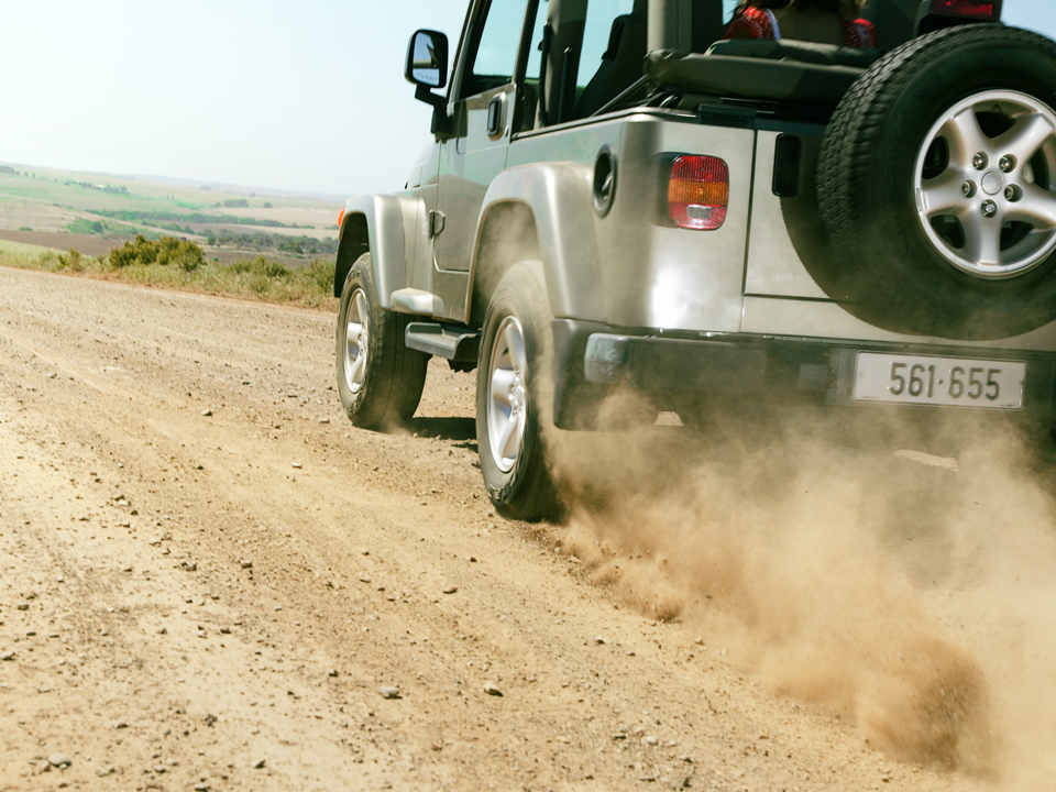 A car with visible aluminium components driving through a desert area.