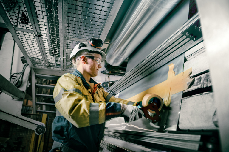 Speira-Mitarbeiter während einer Produktionsphase neben einer Aluminiumspule.