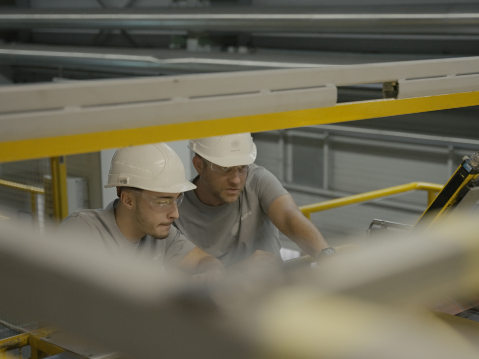 Two Speira employees inspect aluminum sheet for further production.
