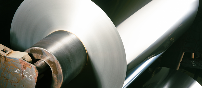 Aluminiumspule, die ein großes, glänzendes Licht in einer Fabrik reflektiert.