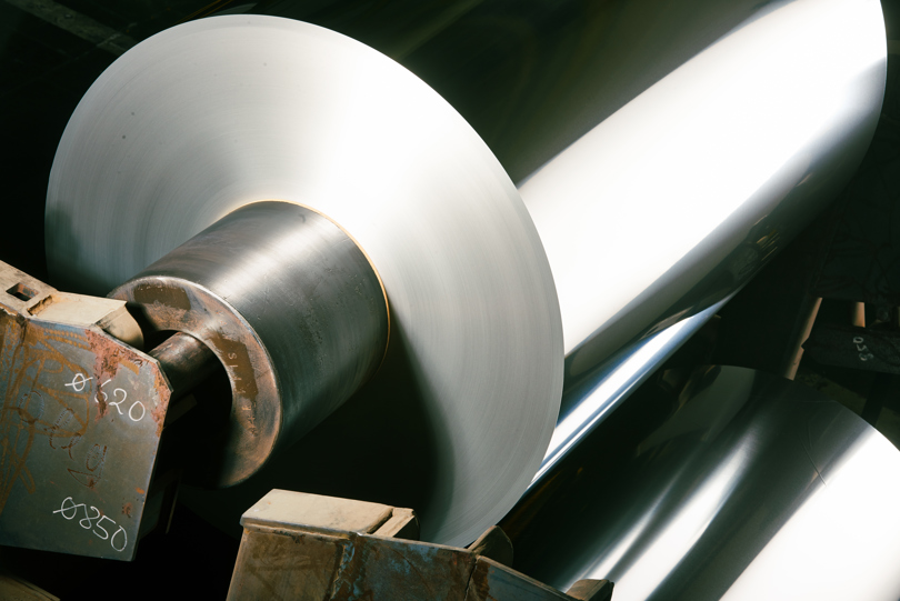 Aluminiumspule, die ein großes, glänzendes Licht in einer Fabrik reflektiert.