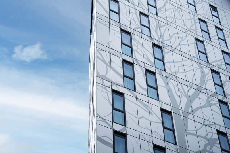 Aluminiumfassade des Kelaty House mit dekorativen Elementen an einem sonnigen Tag.