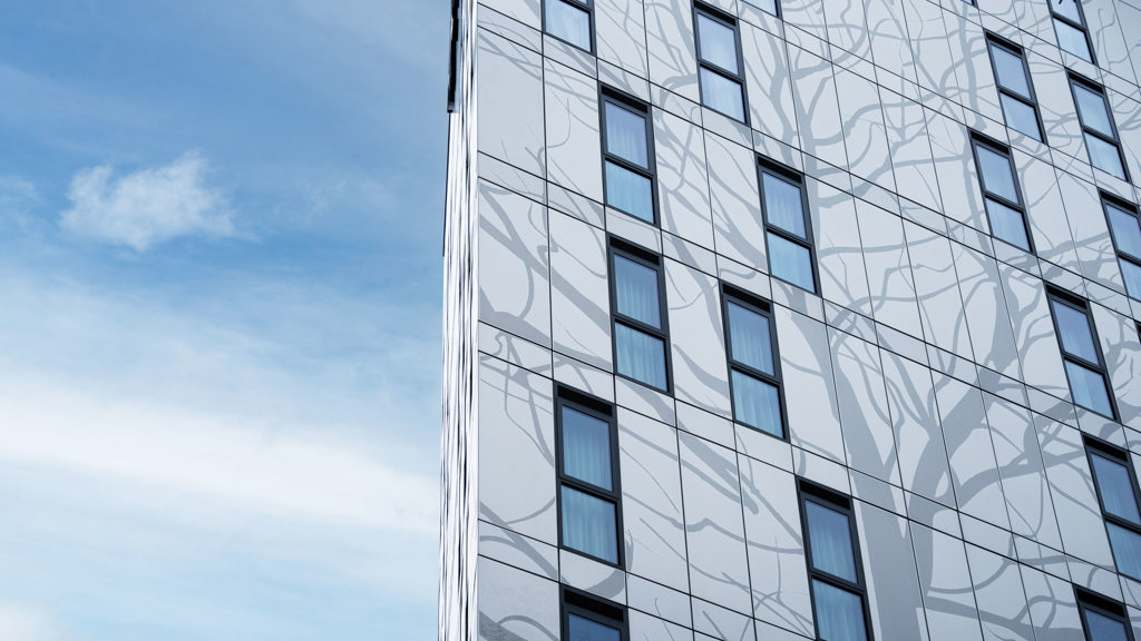 Aluminiumsfasaden på Kelaty House med dekorative elementer på en solrik dag.