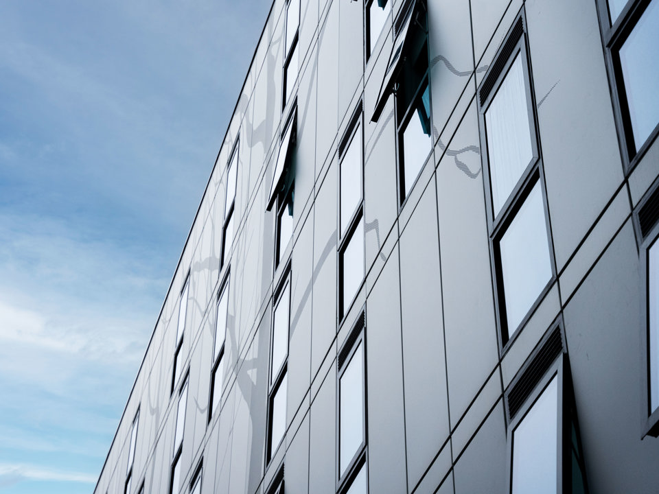 Aluminum façade of Kelaty House with decorative elements on a sunny day.