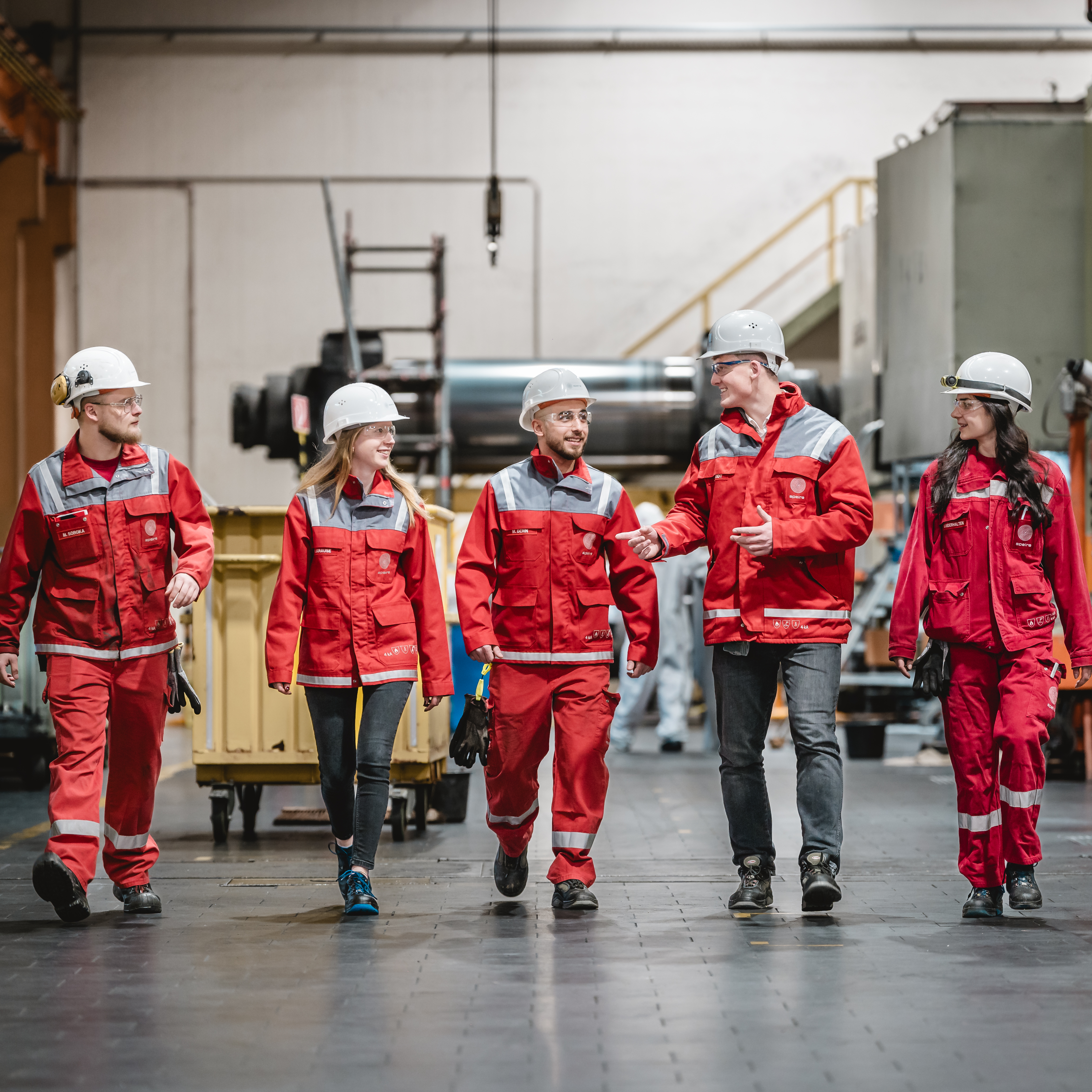 Gruppenbild von fünf Speira Mitarbeitenden, die sich beim Gehen durchs Werk unterhalten.